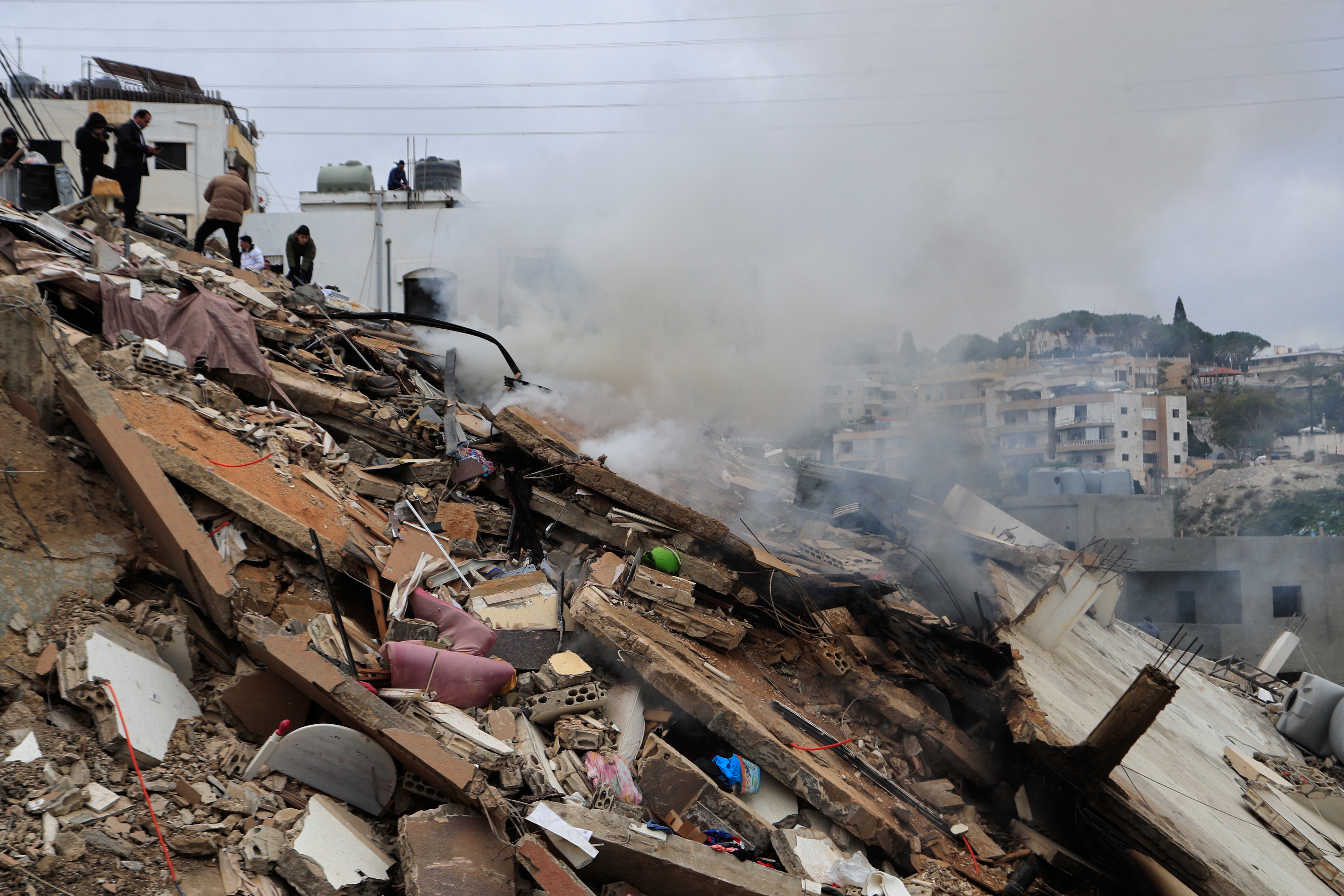  Smoke rises as people inspect a building destroyed in an Israeli strike in the village of Qennarit in southern Lebanon, Thursday, Jan. 22, 2026. (AP Photo/Mohammed Zaatari) 