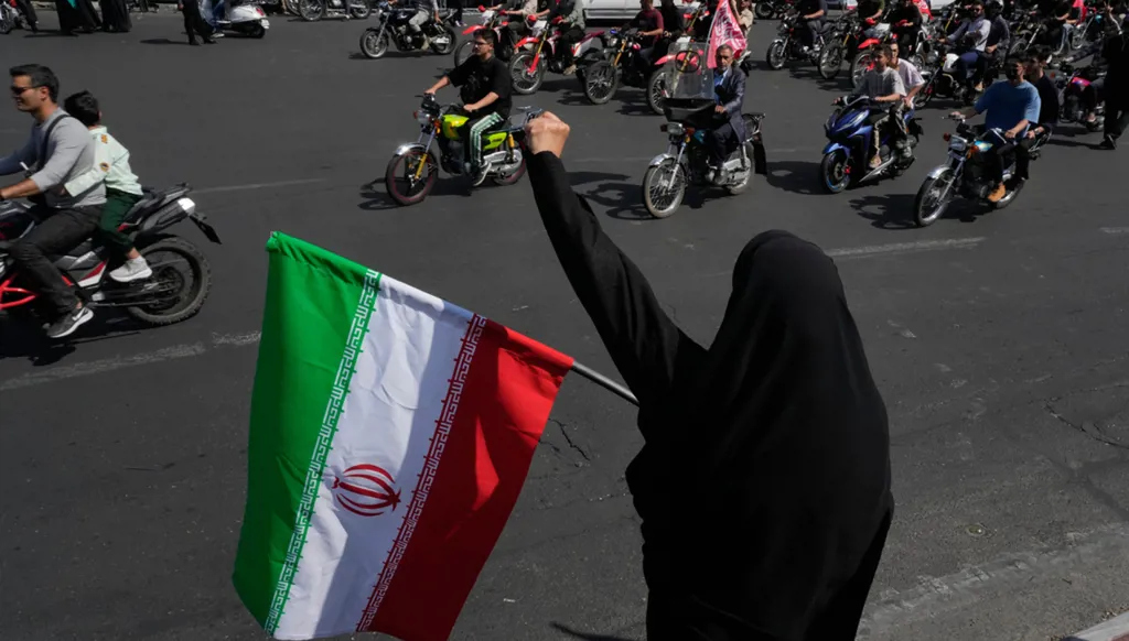 سيدة ترفع العلم الإيراني وتهتف خلال موكب دراجات نارية نظمته الدولة تحت اسم "جانفدا"، أي "التضحية من أجل إيران"، في طهران، 25 أيلول/سبتمبر 2026. (أ ب)