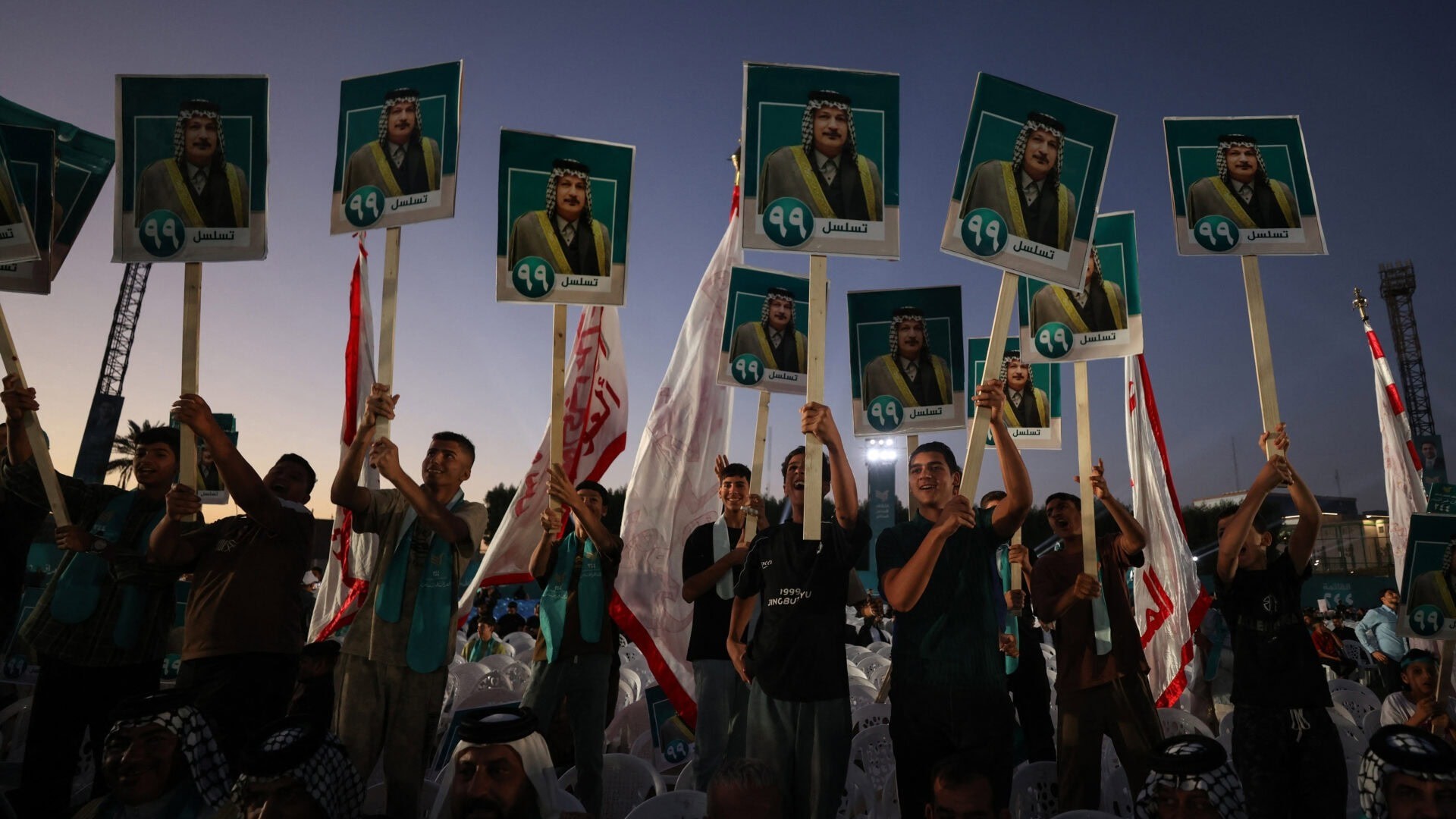 عراقيون يرفعون لافتات لمرشحهم خلال تجمع انتخابي لتحالف المؤسسة العراقية في بغداد في 1 نوفمبر 2025. (أ ف ب)