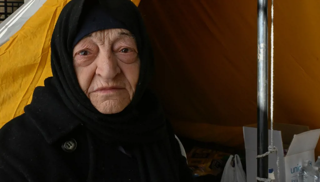 A displaced woman sitting near her tent at the Sports City.