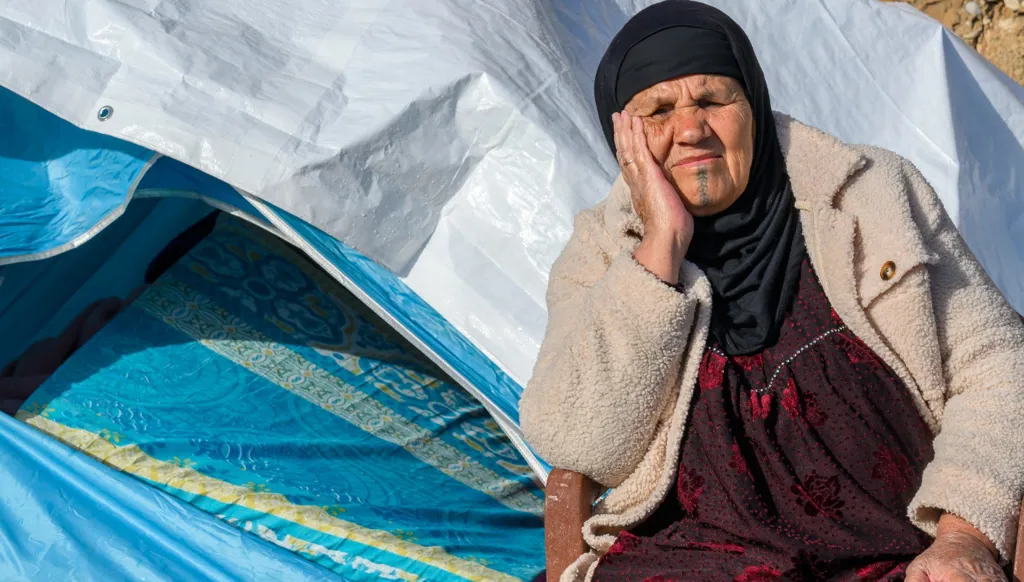 A displaced woman sitting outside her tent in Beirut.