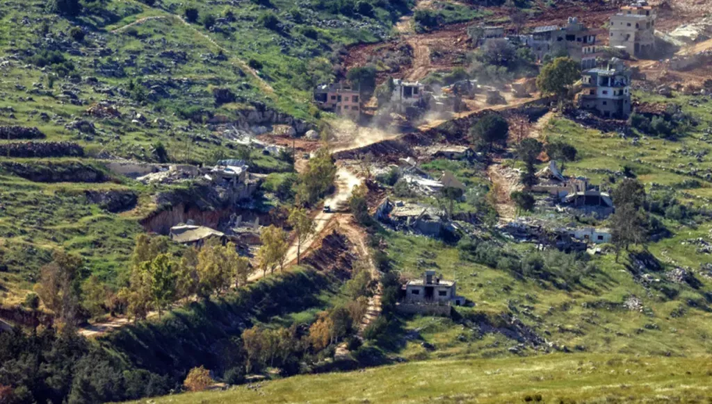 An Israeli military vehicle passes in front of houses destroyed by Israeli airstrikes in southern Lebanon (AFP).
