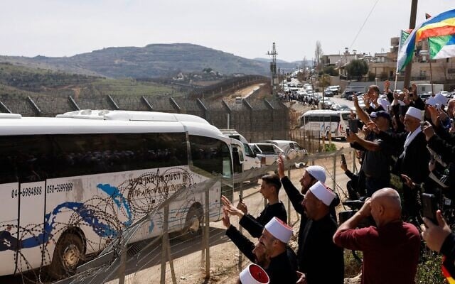 دروز قرب حاجز حدودي بقرية مجدل شمس شمال إسرائيل يلوحون لحافلات تنقل دروزاً من سوريا، 14 مارس 2025. (أ ف ب)
