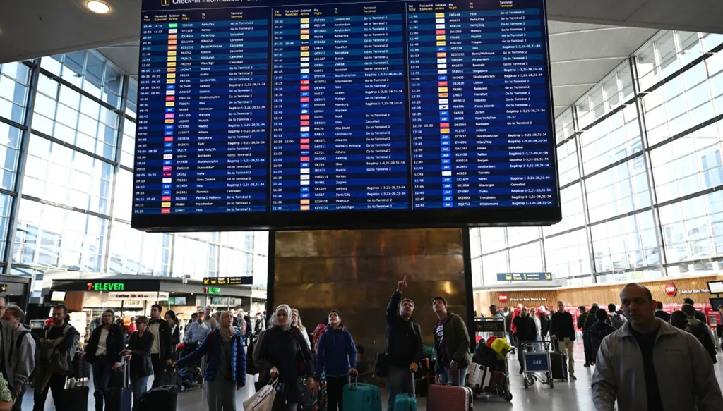 ركاب يتفقدون لوحة معلومات الرحلات في مطار كوبنهاغن (أ ف ب)‏