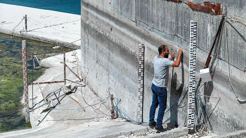 فني يقيس منسوب المياه في سد الثورة (تشرين سابقاً). (أ ف ب)