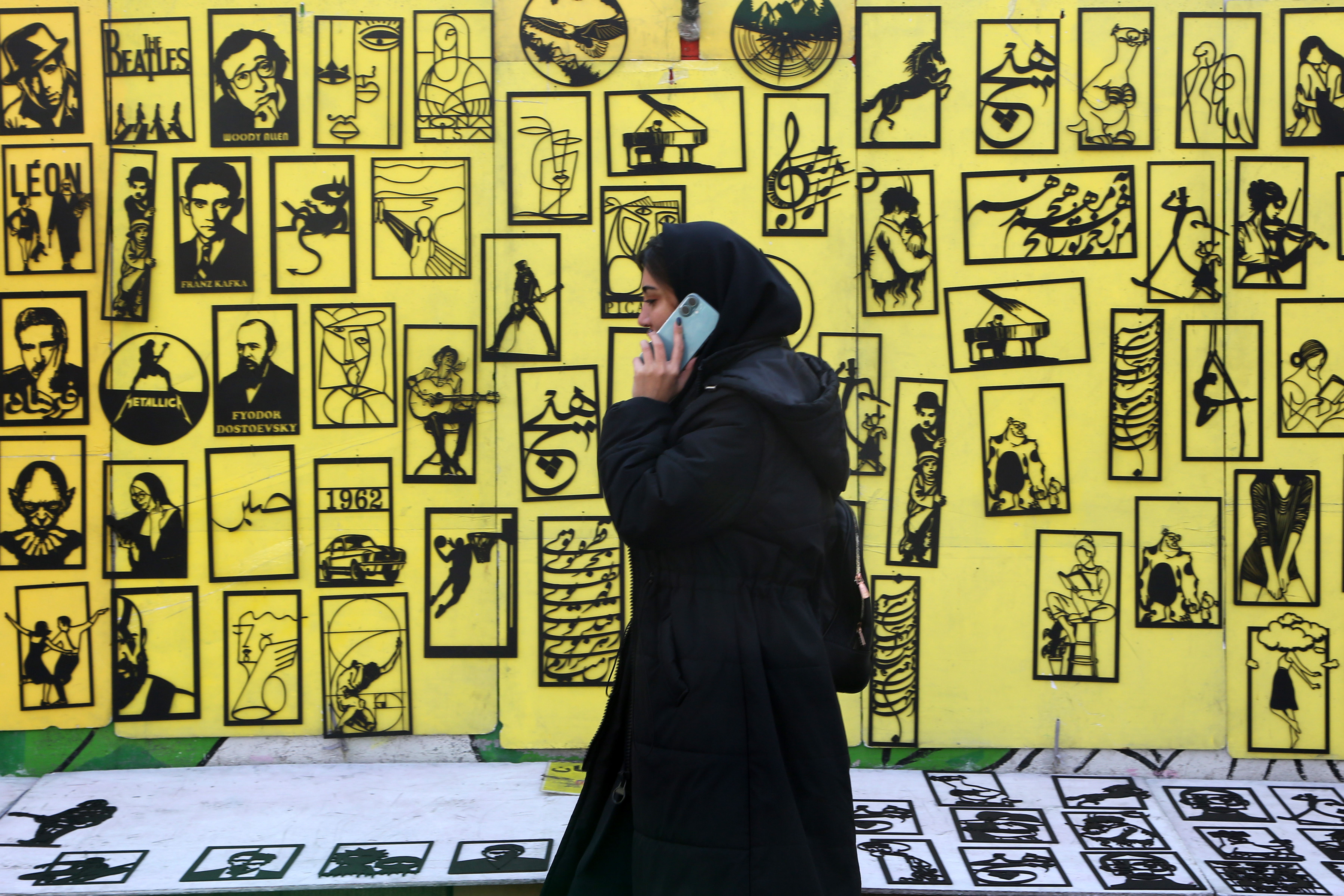 سيدة إيرانية تمرّ أمام جدارية في طهران. (الأناضول)