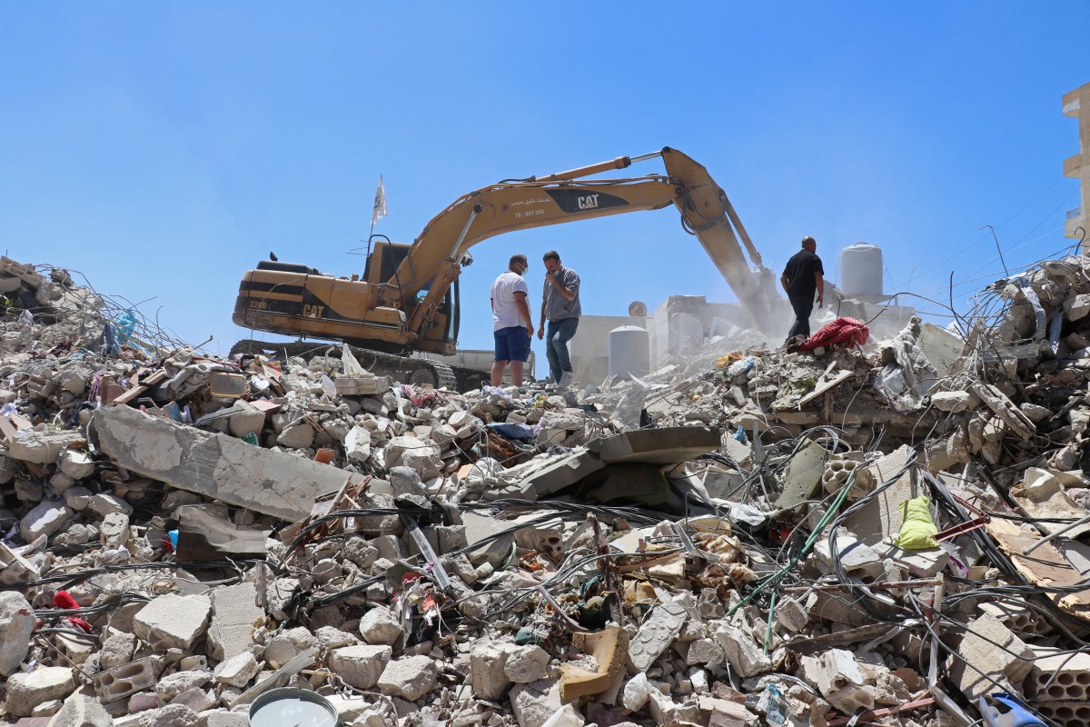حفارة تقوم بإزالة أنقاض المباني المدمرة في منطقة سكنية بمدينة صور في 23 نيسان/أبريل 2026 (أ ف ب)