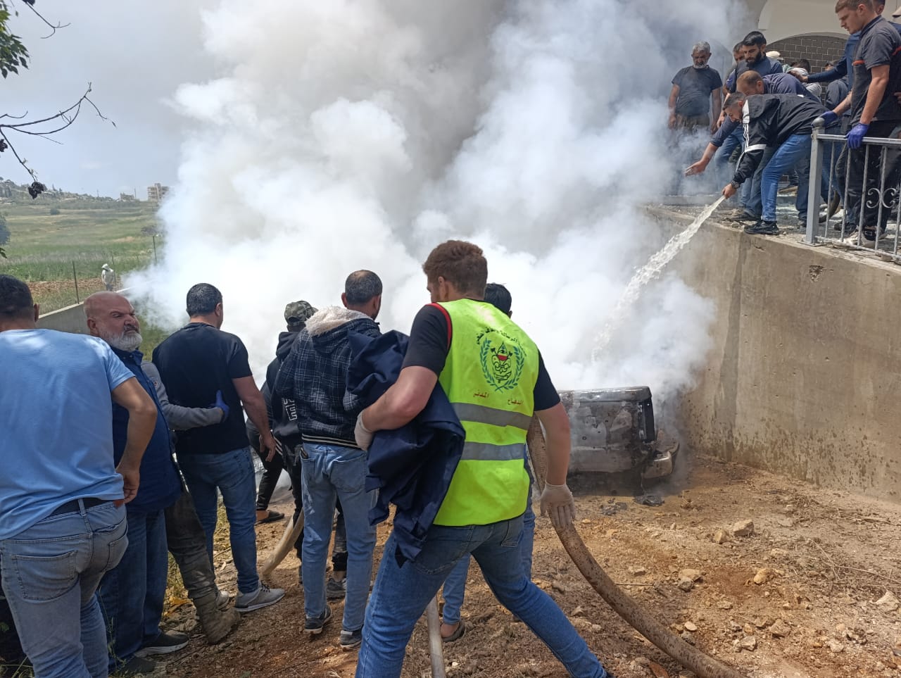 مسعفون ومواطنون يحاولون إخماد النيران في السيارة التي استهدفتها مسيّرة إسرائيلية في ميس الجبل (النهار) 