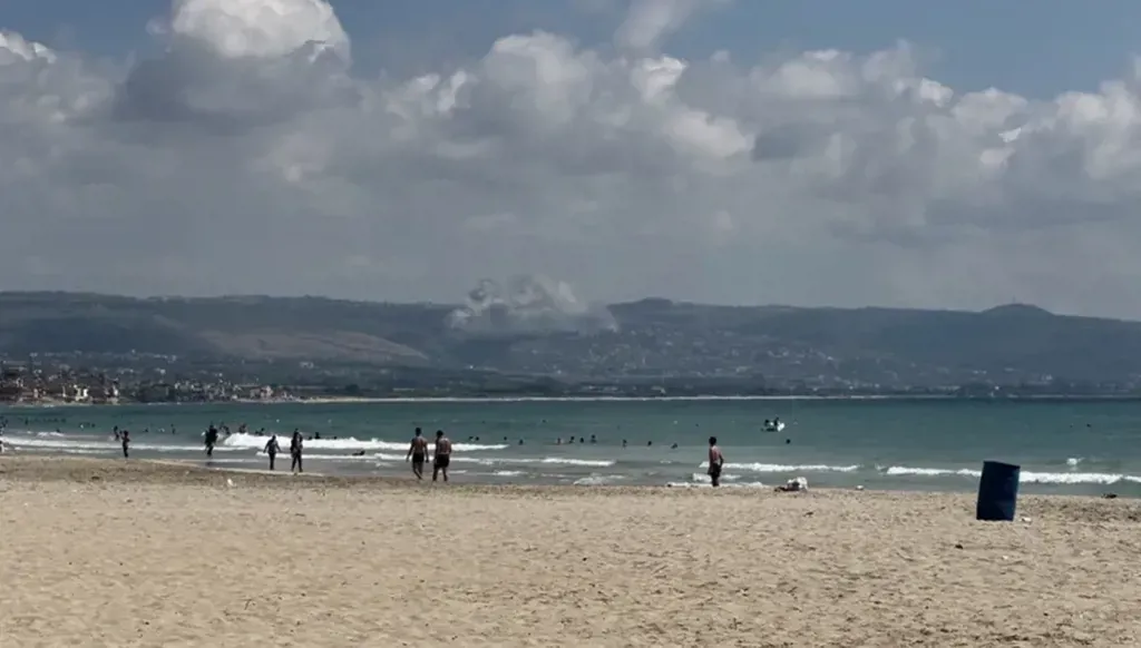La plage de Tyr et ses visiteurs, avec le raid de Mansouri en arrière-plan (Jad Fakih)