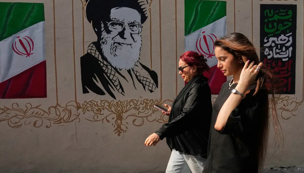 سيدتان تمران أمام صورة للمرشد الإيراني الراحل علي خامنئي وأعلام إيرانية في وسط طهران، 20 آب/أغسطس 2026. (أ ب)