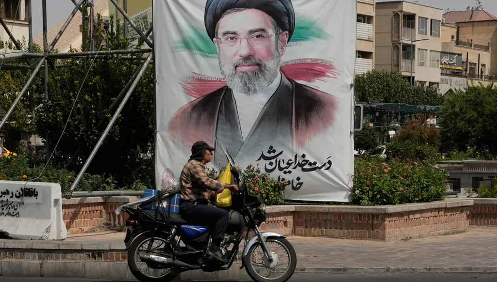 رجل يقود دراجته أمام لافتة تحمل صورة المرشد الإيراني آية الله مجتبى خامنئي في وسط طهران، 31 آب/أغسطس 2026. (أ ب)
