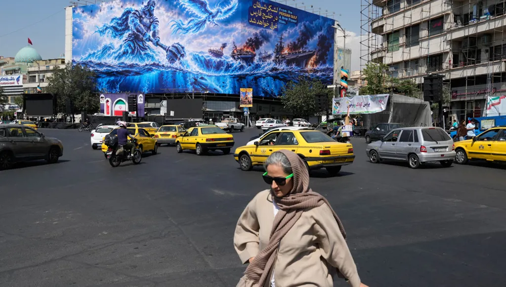 سيدة تمر أمام لوحة دعائية في طهران تتوعد حاملات الطائرات الأميركية بالغرق في الخليج، 14 أيلول/سبتمبر 2026. (أ ب)