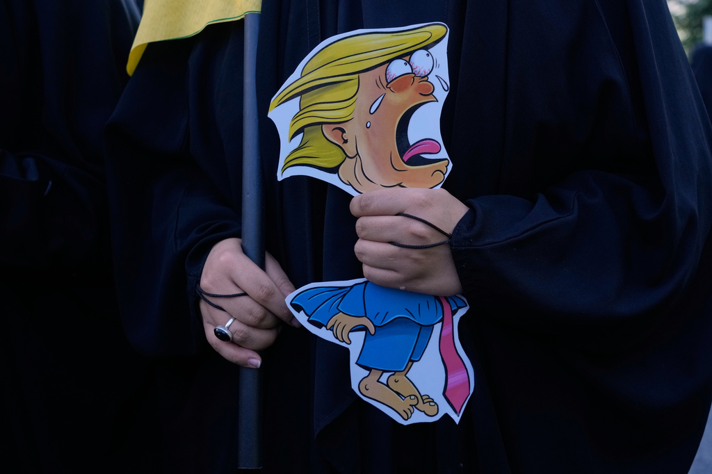 سيدة تحمل رسماً كاريكاتورياً للرئيس الأميركي دونالد ترامب خلال عرض عسكري في طهران، 18 أيلول/سبتمبر 2026. (أ ب)