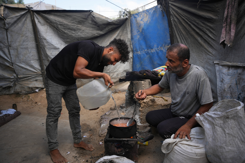 فلسطينيون يستخدمون مواد قابلة للاشتعال جمعوها من مكب للنفايات وقوداً للطهي، بسبب نقص الغاز، في دير البلح وسط قطاع غزة في 22 آب/أغسطس 2026. (أ ب)