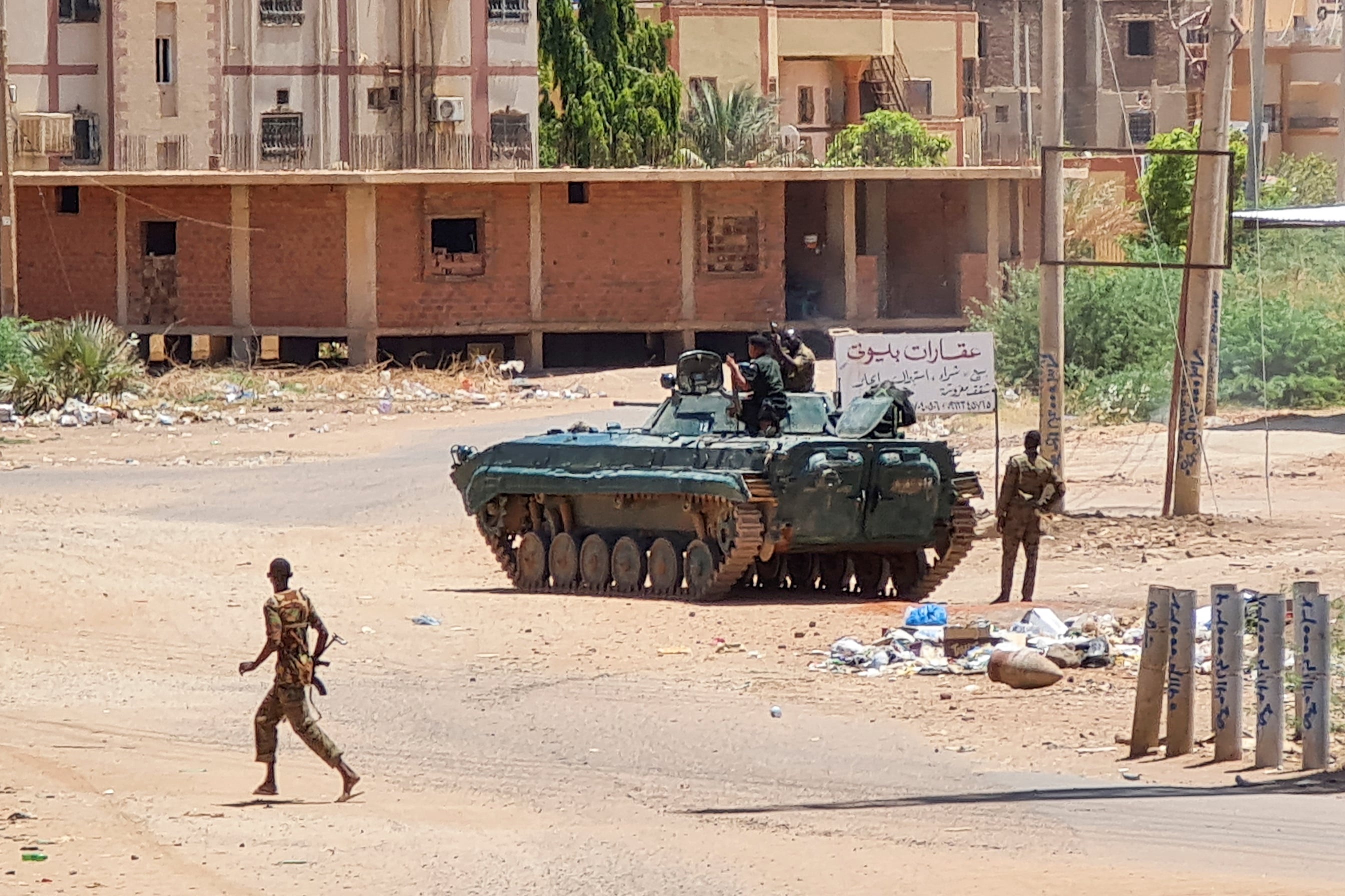 جنود في الجيش السوداني يمشون قرب مركبة مدرعة في شارع بجنوب الخرطوم، 6 مايو 2023. (فرانس برس)