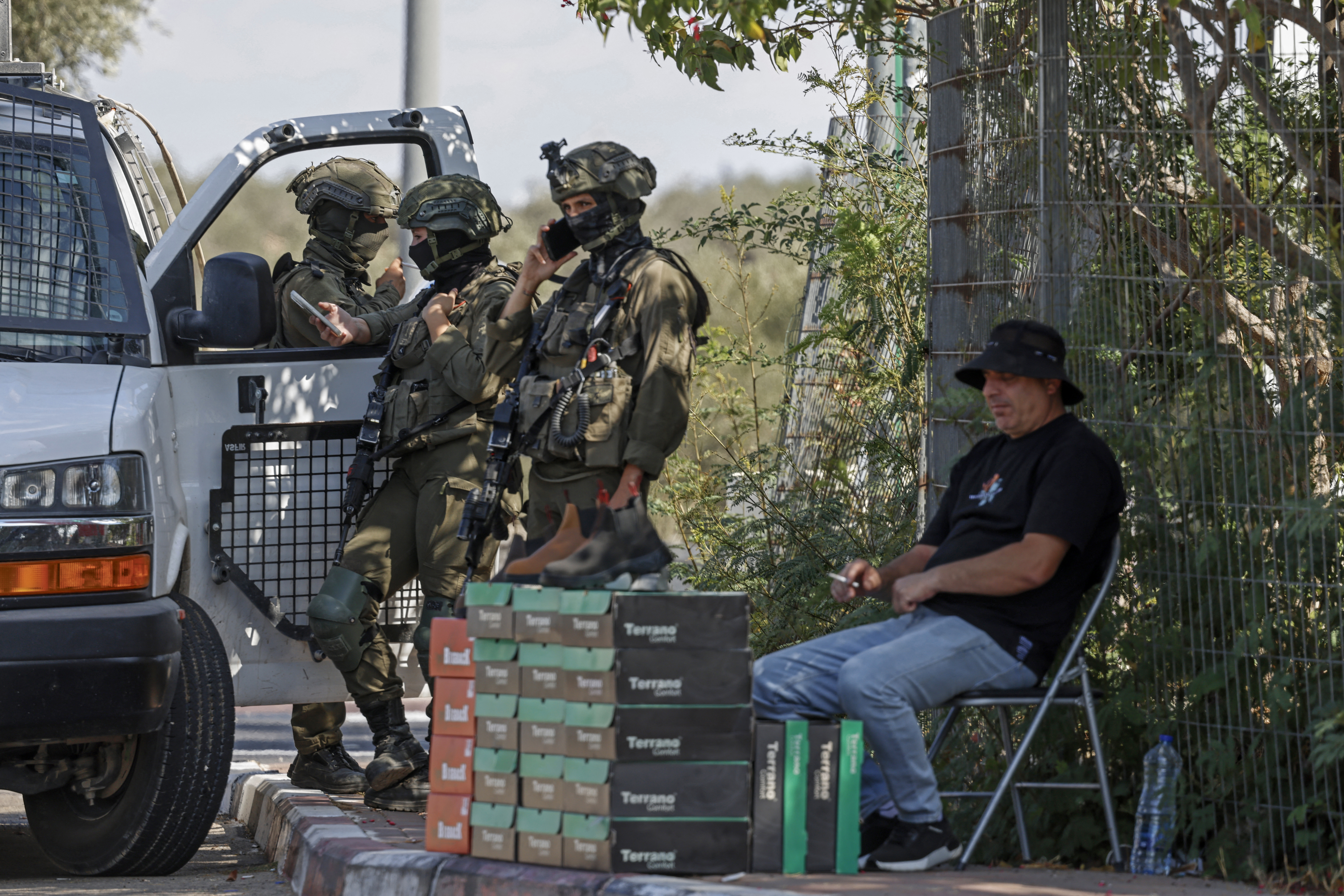 جنود إسرائيليون يقفون بجانب بائع فلسطيني على جانب الطريق في قرية رنتس قرب رام الله في الضفة الغربية المحتلة (أ ف ب)