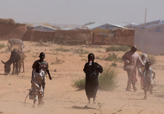 لاجئون سودانيون من دارفور يسيرون وسط عاصفة رملية في مخيم تولوم للاجئين في شرق تشاد (رويترز)