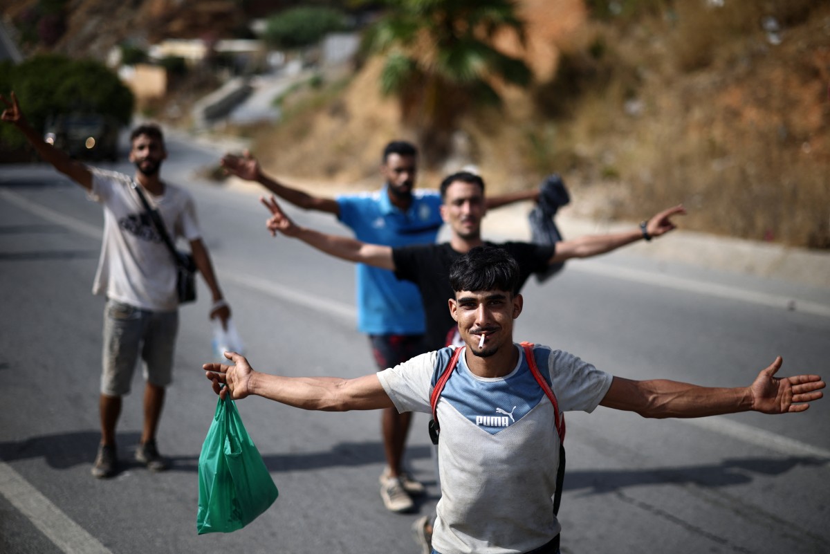 مهاجرون أثناء مرافقتهم إلى الحدود بين سبتة والمغرب في جيب سبتة الإسباني (أ ف ب)