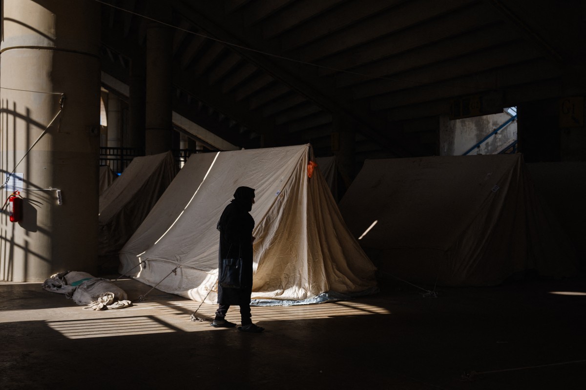 امرأة مسنة نازحة تقف بجوار خيمتها في ملعب مدينة كميل شمعون الرياضية في بيروت (أ ف ب)