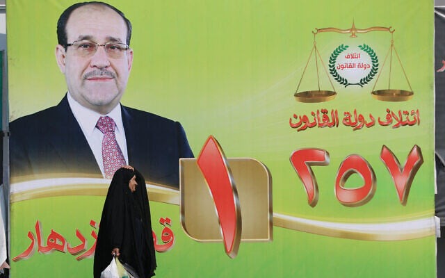 امرأة تمر بلوحة إعلانية انتخابية تحمل صورة لرئيس الوزراء العراقي السابق نوري المالكي في وسط بغداد، في 19 أكتوبر 2025. (أ ف ب)
