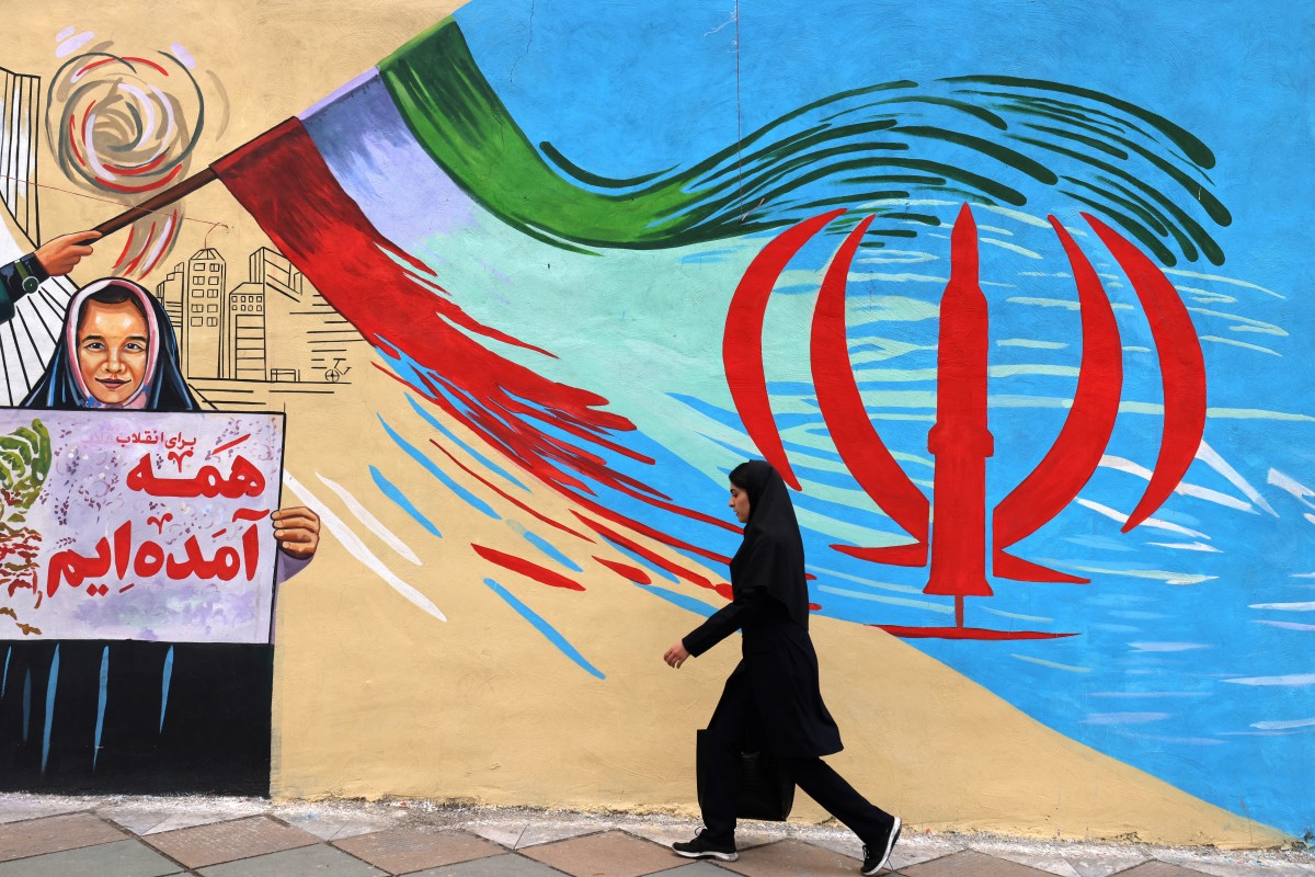 امرأة إيرانية تسير أمام جدارية مناهضة للولايات المتحدة الأميركية وإسرائيل في طهران (أ ف ب)