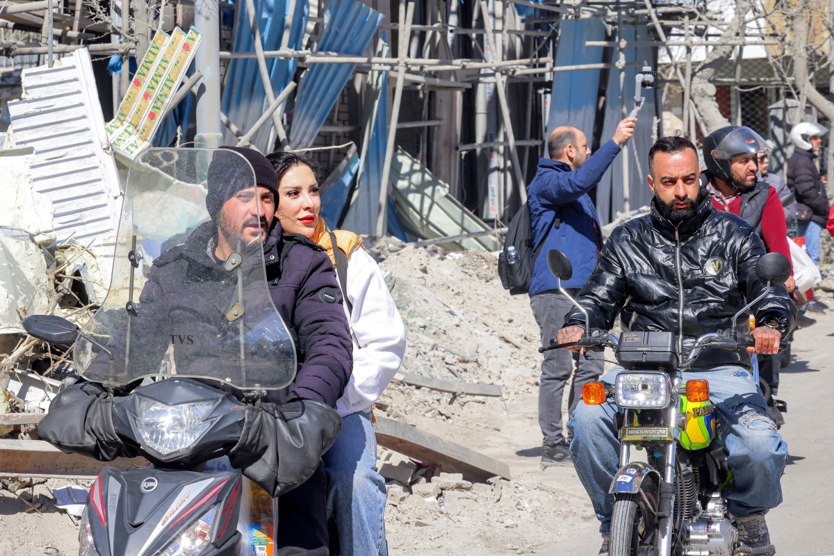 مواطنون إيرانيون أمام المباني المدمرة والمتضررة بالقرب من ميدان فردوسي في طهران في 3 آذار/مارس 2026 (أ ف ب)