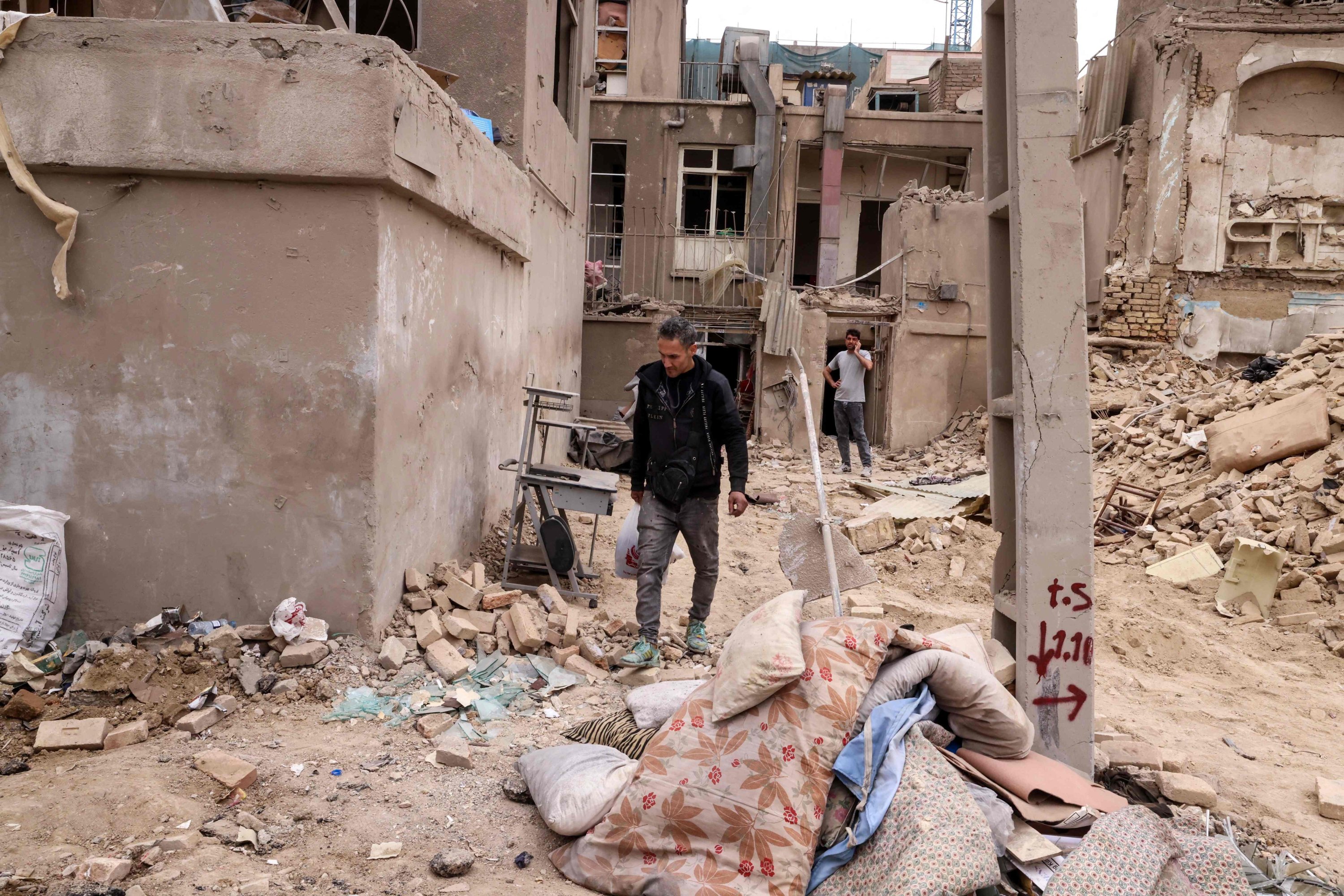 مواطن إيراني يجمع أغراضه الشخصية من المباني المدمرة عقب غارة عسكرية على العاصمة طهران، إيران، 15 آذار/مارس 2026 (أ ف ب)