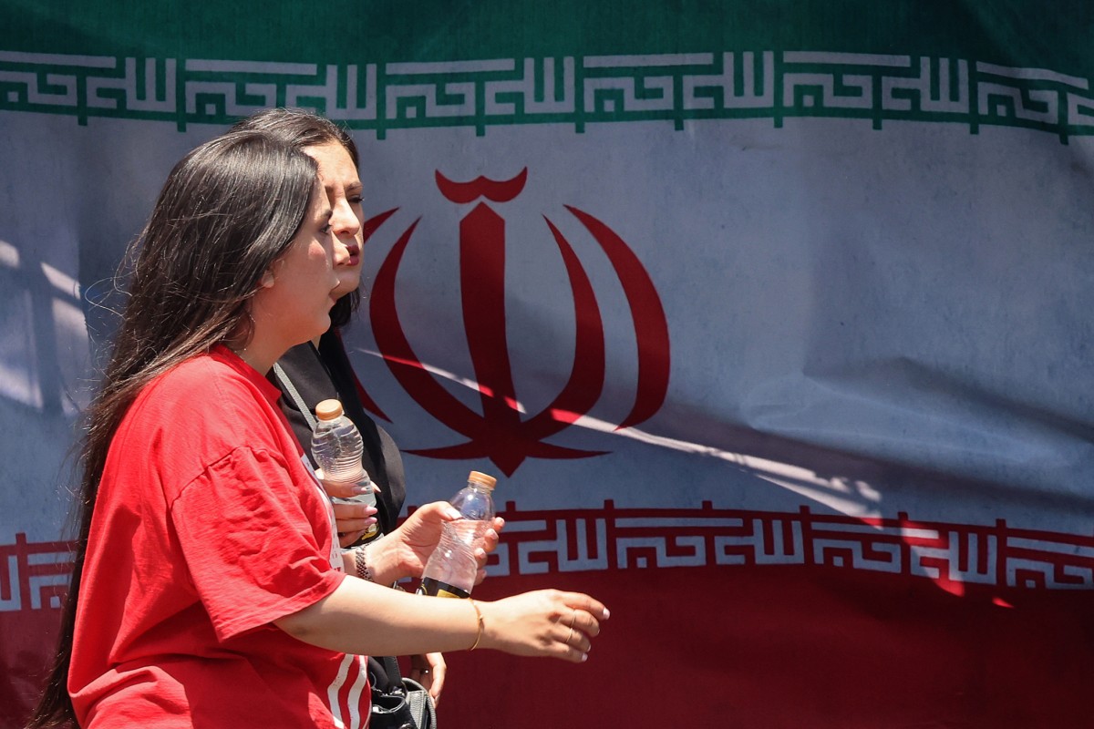 نساء يمررن أمام العلم الوطني الإيراني في ساحة فاناك في طهران في 10 يونيو 2026 (أ ف ب)