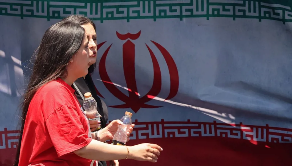 نساء يمررن أمام العلم الوطني الإيراني في ساحة فاناك في طهران في 10 يونيو 2026 (أ ف ب)