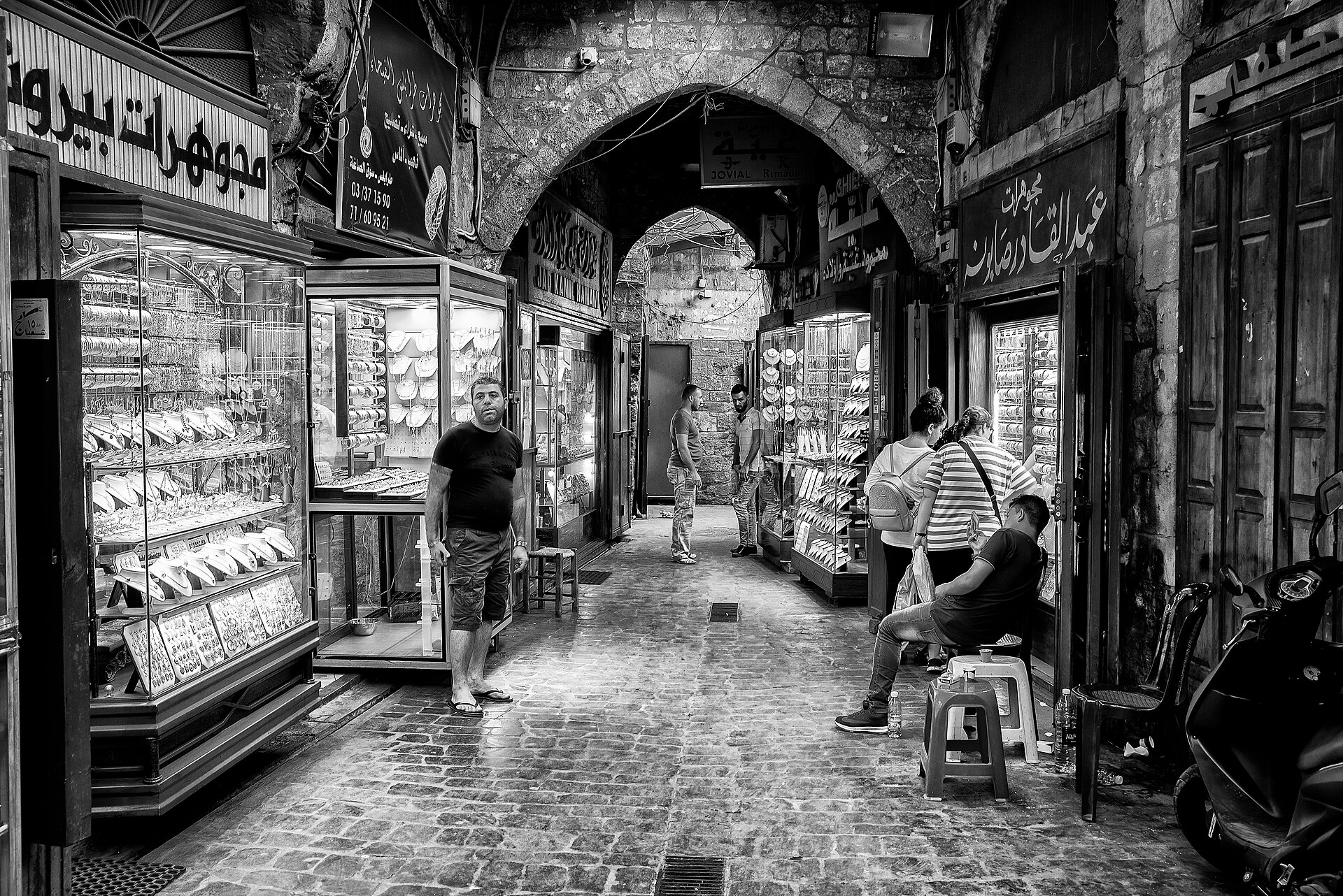 أحد الممرات المسقوفة في سوق طرابلس القديم، حيث تصنع الأقواس وتقارب المباني مساحات مظلّلة تخفّف التعرّض المباشر للشمس. (Wikimedia)