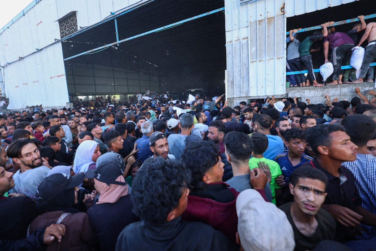 فلسطينيون ينقلون أكياساً من المساعدات الغذائية أثناء اقتحامهم مستودعاً تابعاً لبرنامج الأغذية العالمي في دير البلح (أ ف ب)