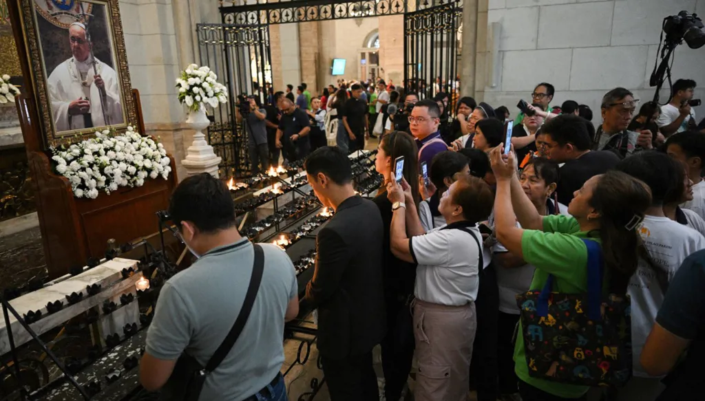 مؤمنون يصلون أمام صورة البابا فرنسيس في كاتدرائية مانيلا (أ ف ب)‏