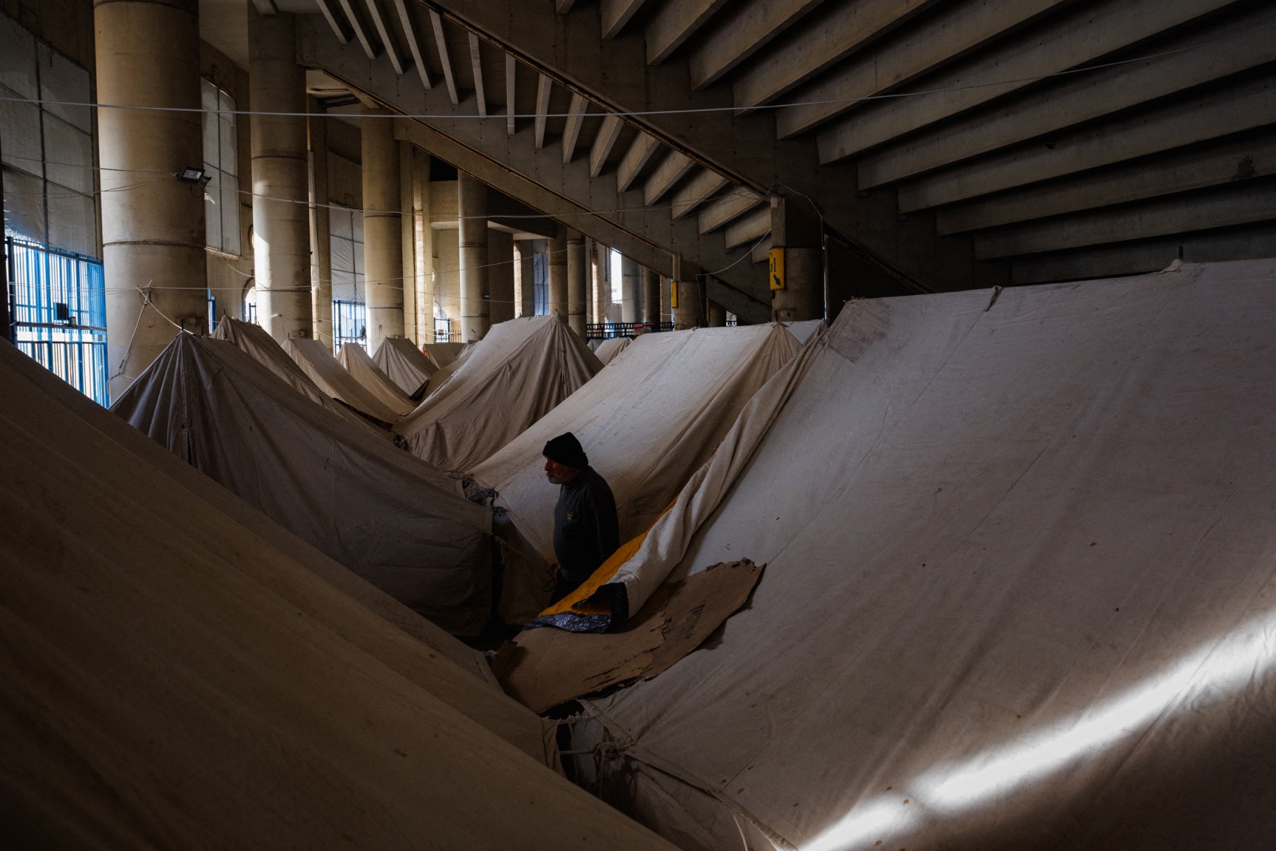 رجل نازح يقف بجوار الخيام المنصوبة في ملعب مدينة كميل شمعون الرياضية في بيروت (أ ف ب)