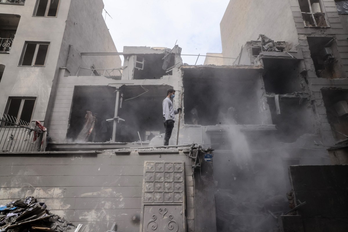 رجل إيراني يقف على جدار من المنازل المتضررة في أعقاب غارة عسكرية على العاصمة الإيرانية طهران في 15 آذار/مارس 2026 (أ ف ب)