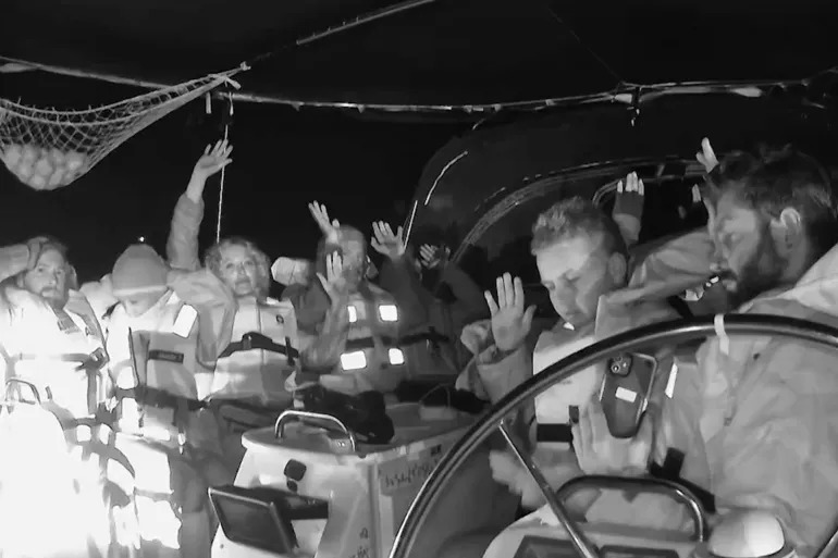 صورة نشرها الناشطون وهم يرفعون أيديهم لحظة الاقتحام الإسرائيلي لإحدى سفن الأسطول خلال إبحاره لكسر الحصار عن غزة (أسطول الصمود)