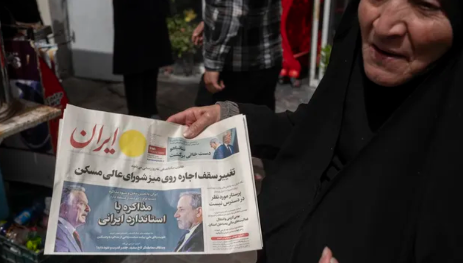 امرأة إيرانية تحمل صحيفة تحمل صور وزير الخارجية الإيراني عباس عراقجي وستيف ويتكوف، المبعوث الخاص للبيت الأبيض، في طهران (نور فوتو)