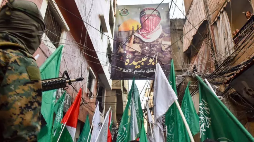 صورة أبو عبيدة وأعلام حماس في أحد المخيمات الفلسطينية في لبنان (غيتي)