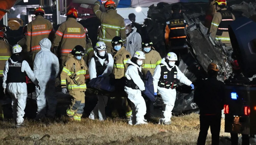 رجال الإطفاء وأفراد الإنقاذ يحملون جثة أحد الضحايا بالقرب من مكان تحطم طائرة شركة جيجو. 
