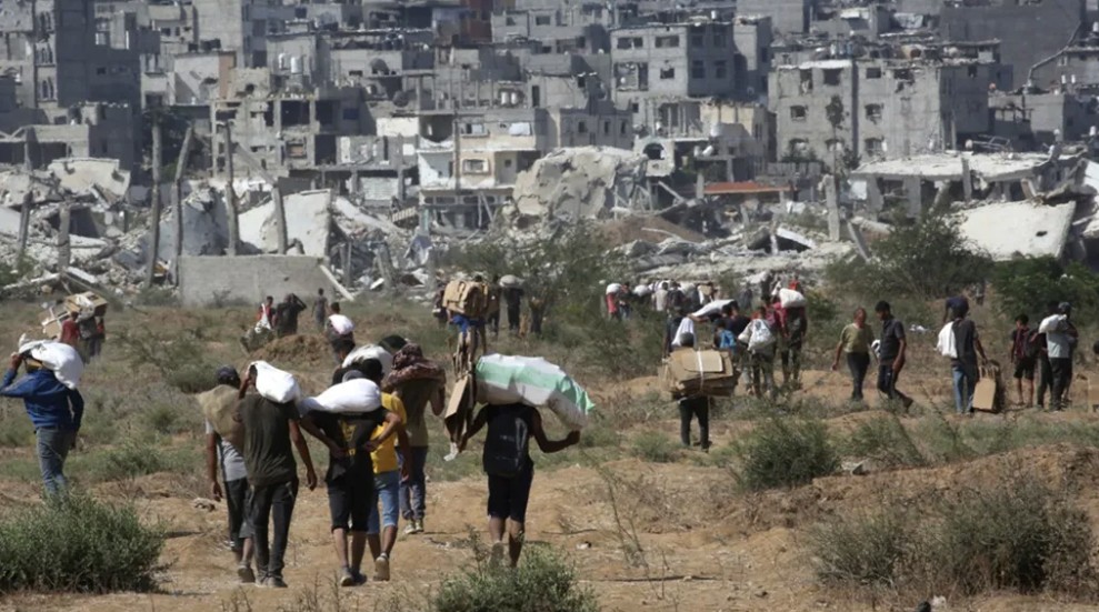 فلسطينيون نازحون في مخيم النصيرات للاجئين يحملون طرود غذائية ومواد أخرى (أ ف ب)