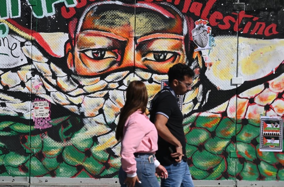 مارة أمام جدارية رسمها في مكسيكو سيتي (أ ف ب)