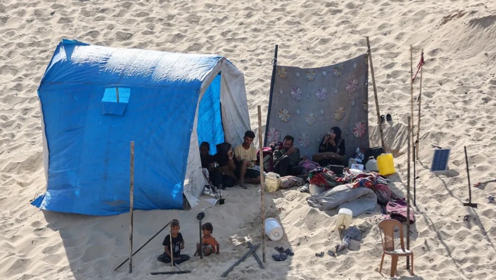 فلسطينيون يجلسون بجوار خيمة في مخيم للنازحين في خان يونس جنوب قطاع غزة. (أ ف ب)