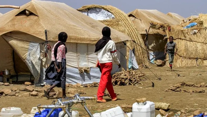 فتيات يمررن أمام خيام في مخيم للنازحين (أ ف ب)