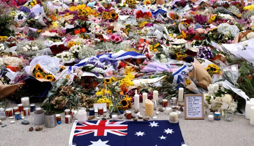 زهور وعلم أسترالي موضوعة تكريماً لضحايا حادث إطلاق النار في شاطئ بوندي. (أ ف ب)