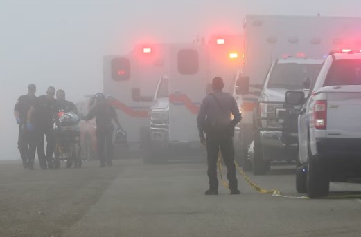 طاقم الطوارئ ينقلون ضحية حادث تحطم طائرة صغيرة إلى سيارة إسعاف تنتظرهم (أ ب)