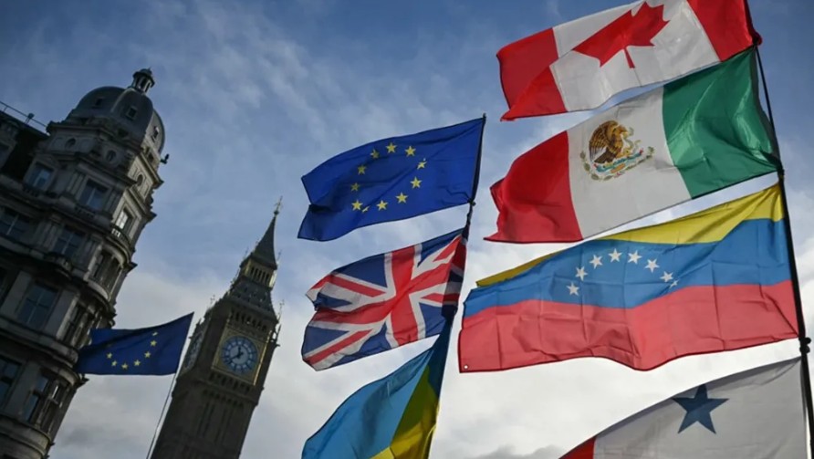 أعلام (من أعلى في اتجاه عقارب الساعة) الاتحاد الأوروبي وكندا والمكسيك وفنزويلا وبنما وغرينلاند (أسفل اليسار) وأوكرانيا والمملكة المتحدة ترفرف في الهواء بينما يرفعها المتظاهرون في الشارع خارج مبنى البرلمان في وسط لندن. (أ ف ب)