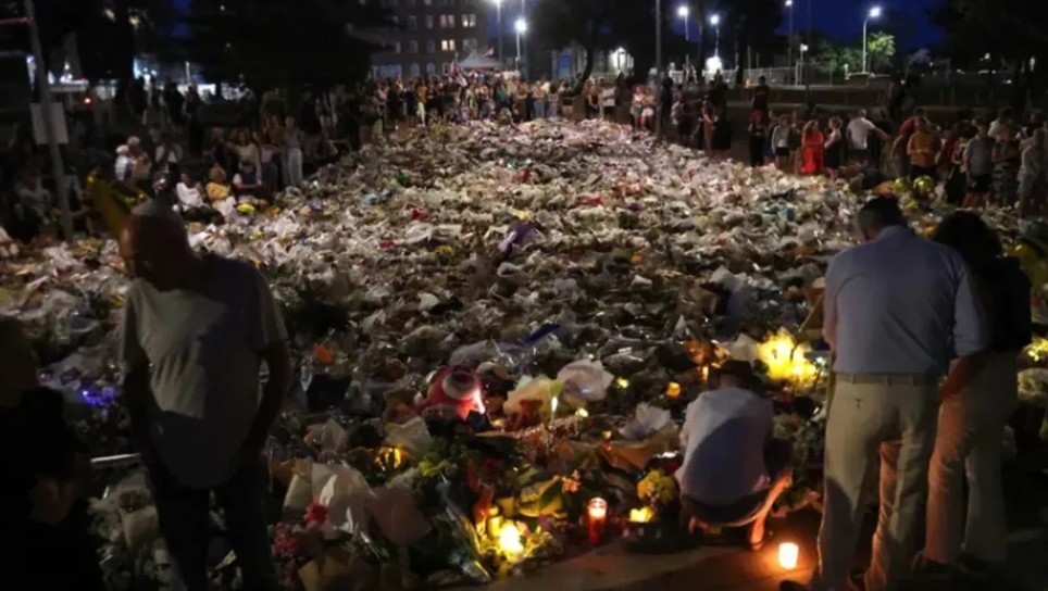 يتجمع المشيعون بجانب الزهور الموضوعة تكريماً لضحايا حادث إطلاق النار في شاطئ بوندي، في سيدني في 20 كانون الأول / ديسمبر 2025. (أ ف ب)