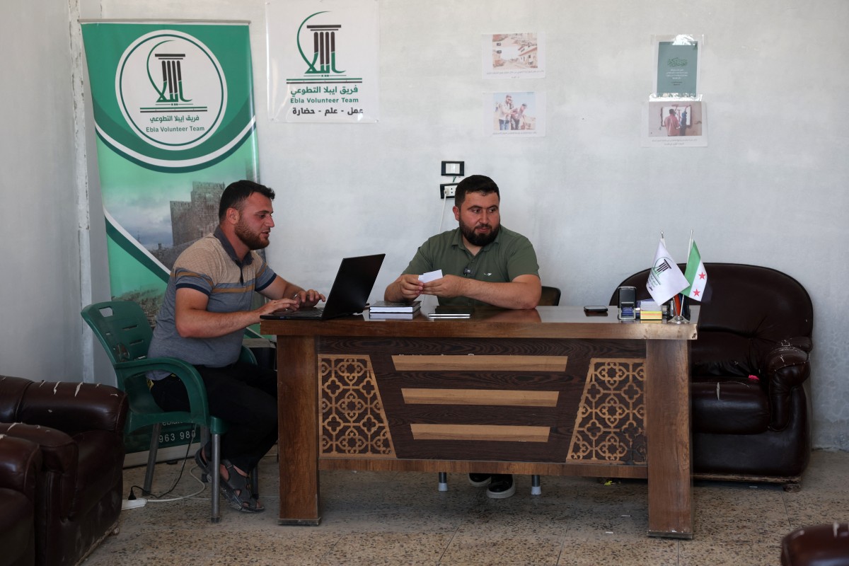 المهندس المعماري عبد العزيز المحمد يعمل مع زميل له في قريته تل مرديخ (أ ف ب)‏