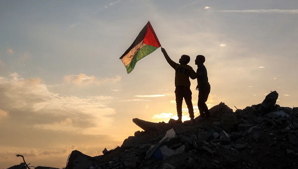 طفلان يرفعان العلم الفلسطيني على أنقاض منزل في غزة (أ ف ب)