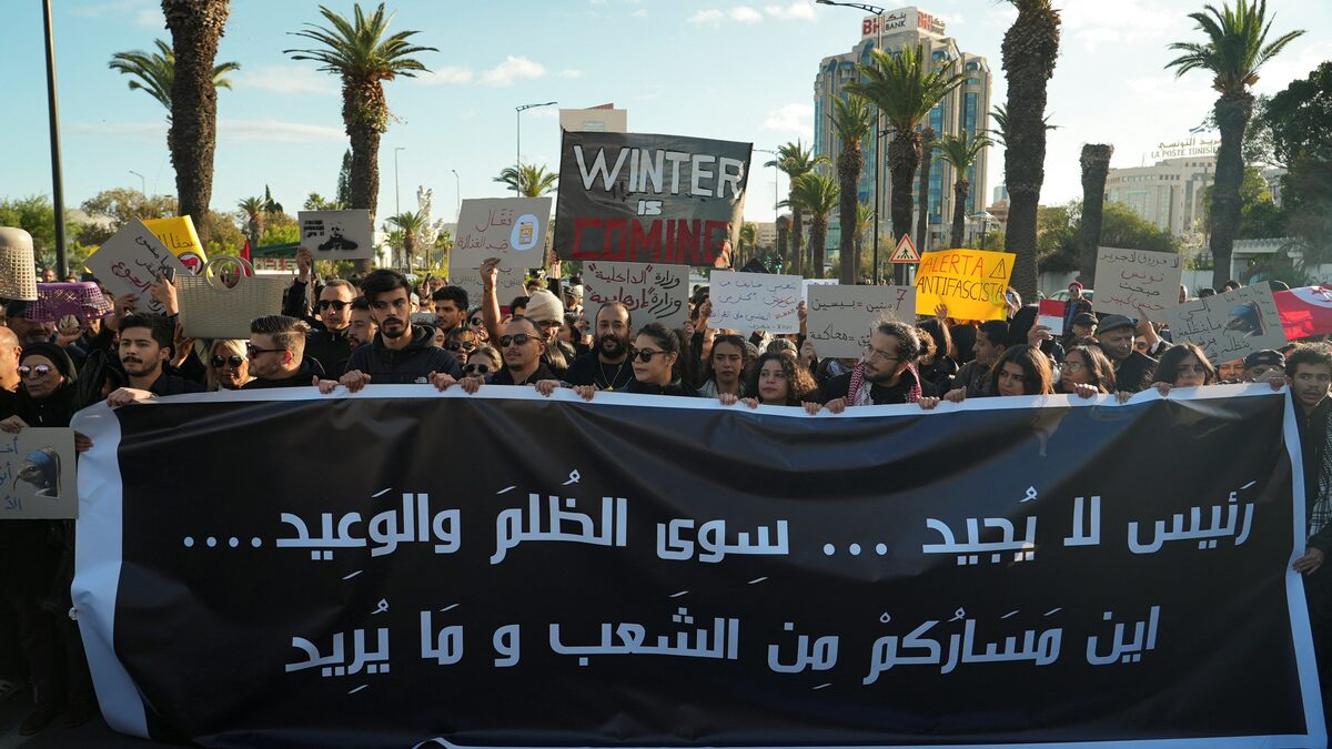 تونسيون في مسيرة احتجاجية ضد الرئيس قيس سعيد حاملين لافتة يتهمونه خلالها بتكريس حكم الفرد في العاصمة تونس (رويترز)