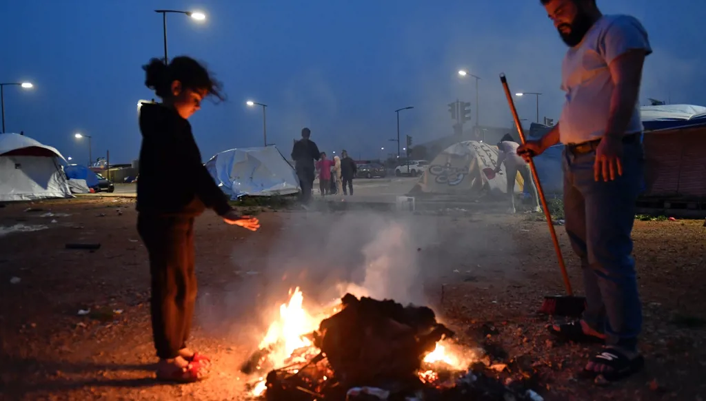 Two displaced people trying to keep warm in cold weather.